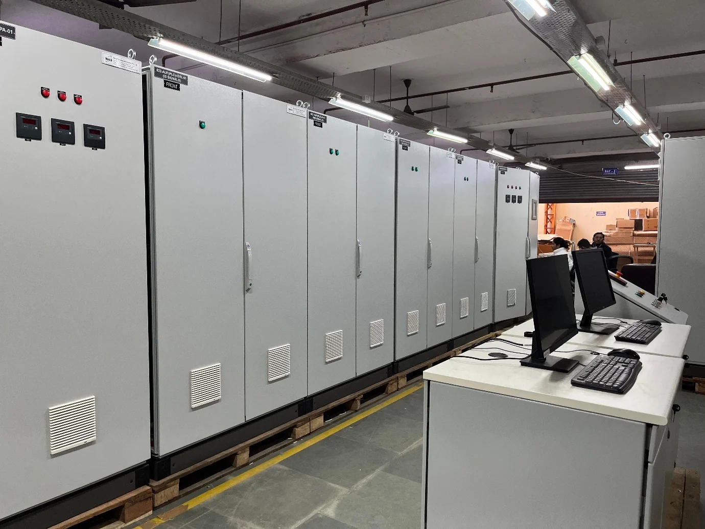 Long line of completed industrial control panels with operator stations